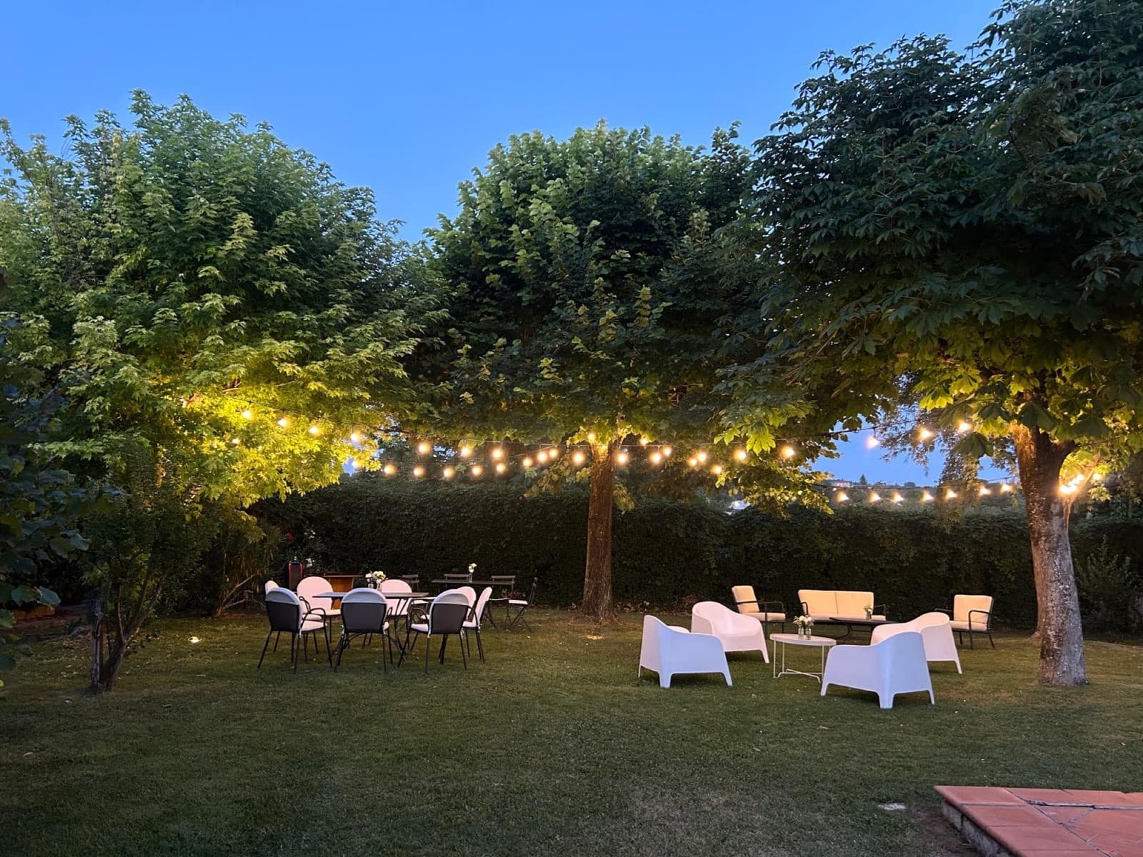 Il giardino al tramonto con le luci sospese tra gli alberi
